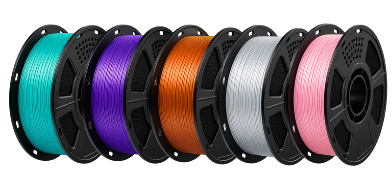 five spools of 3D printer filament, green, purple, copper, silver, and pink